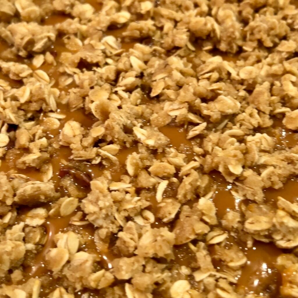 crumbly oat mixture on top of caramel before baking carmelita bar cookies.